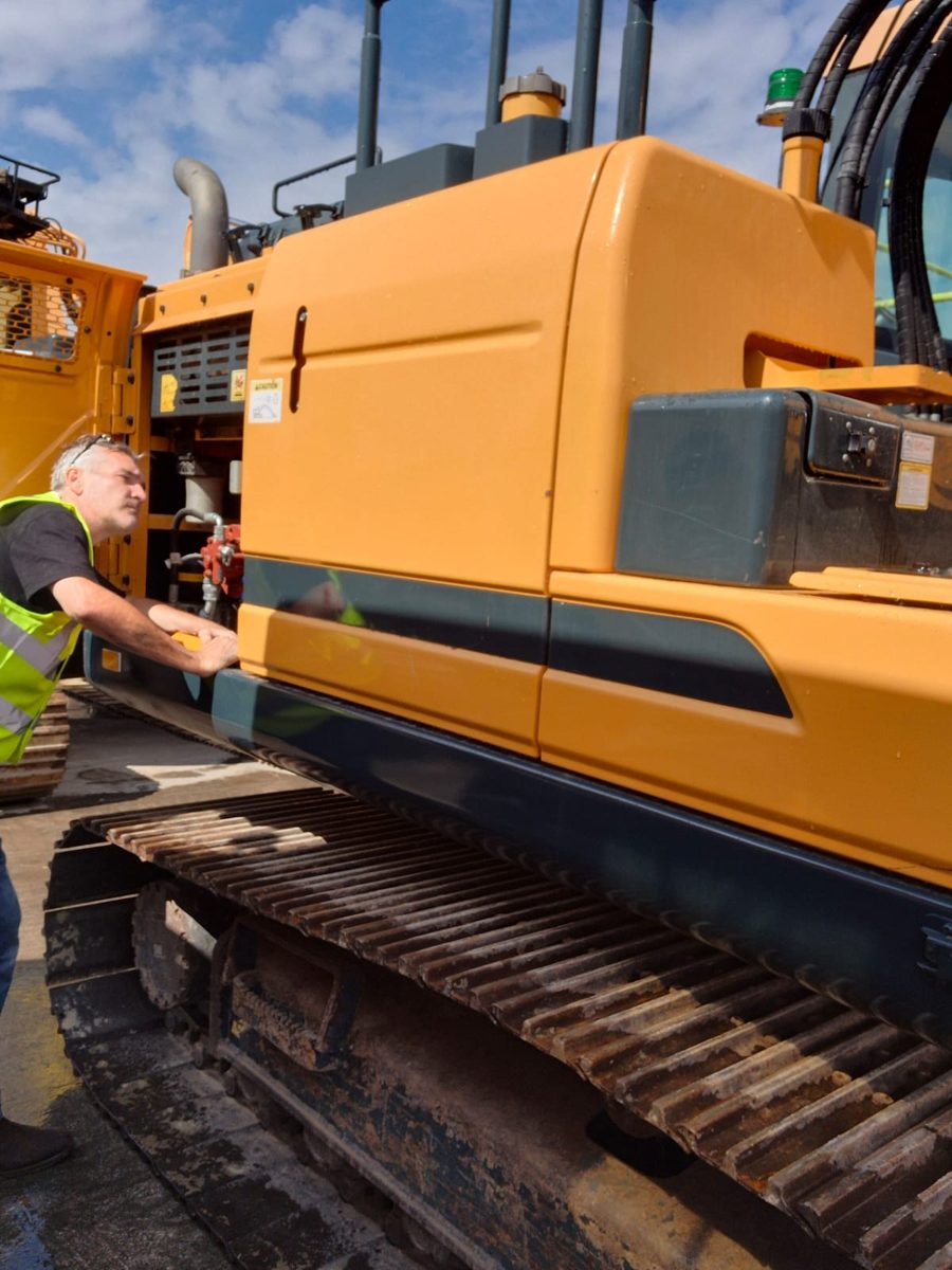 Rob McNinch inspecting a machine's undercarriage